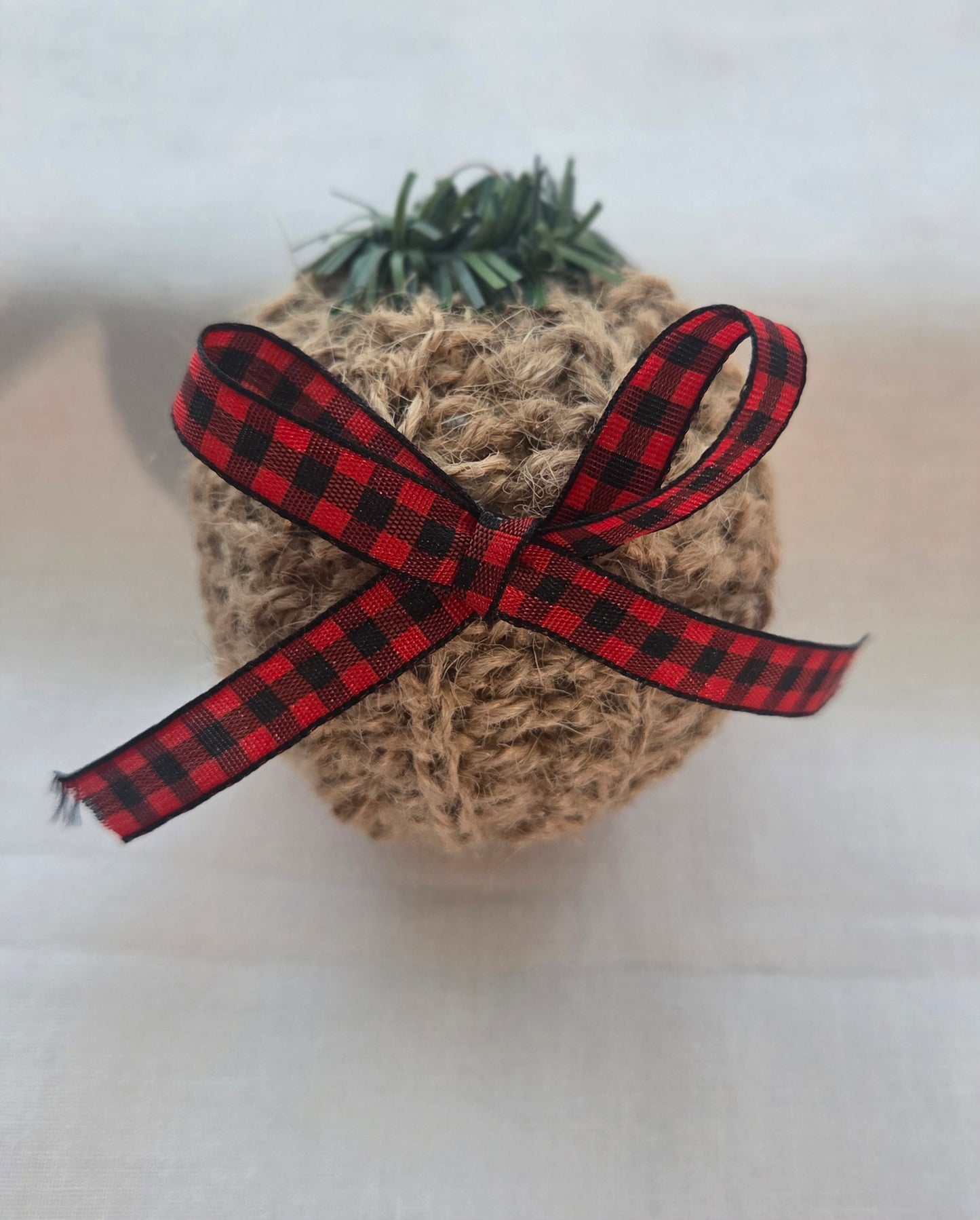 Rustic Christmas ornament with jute twine, red plaid ribbon bow, and faux greenery top