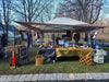Handmade craft market booth displaying crochet items, framed art, and cozy gifts outdoors.