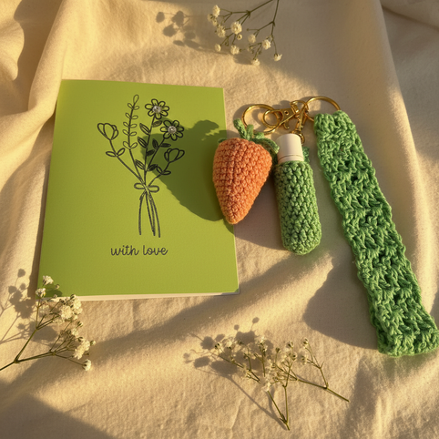 Handmade crochet keychains and green card with flowers on fabric, cozy gift set by Erika Liesel.