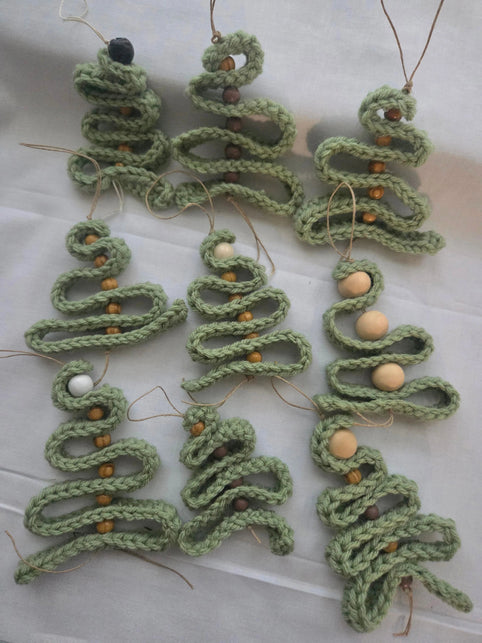 Handmade crochet Christmas tree ornaments with wooden beads on a white cloth, Erika Liesel