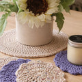 Handmade crochet coasters and placemat with sunflower decor and candle on wooden table