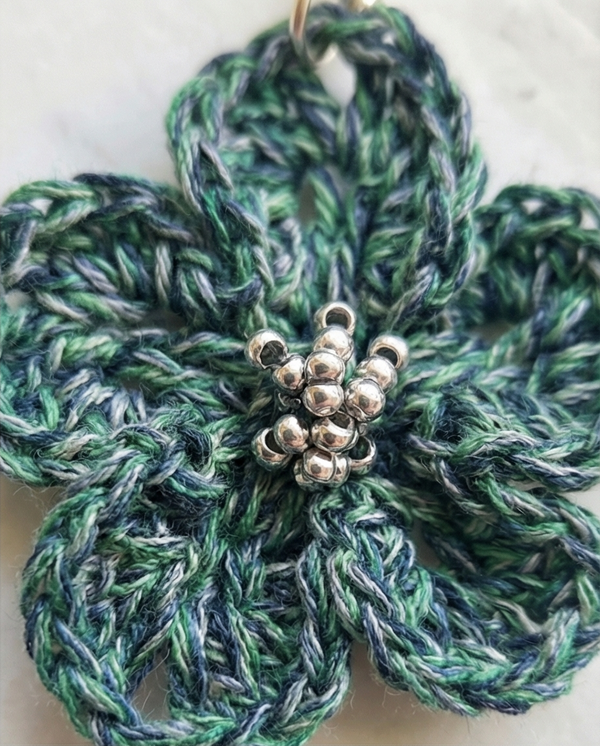 Handmade crochet flower earrings in pink, red, and blue on a marble surface