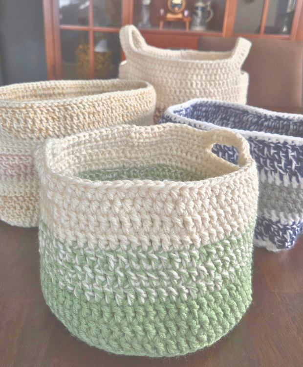 Handmade crochet storage baskets in assorted colors on a wooden table