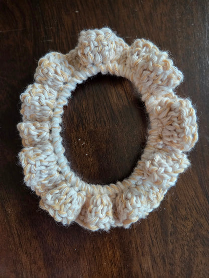 Beige handmade crochet scrunchie on dark wood surface