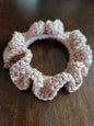 Pink crochet ruffle scrunchie on dark wooden surface