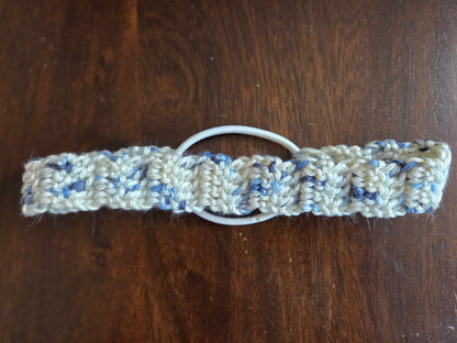 Handmade crocheted white and blue hair tie on dark wood table
