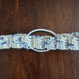 Handmade crocheted white and blue hair tie on dark wood table