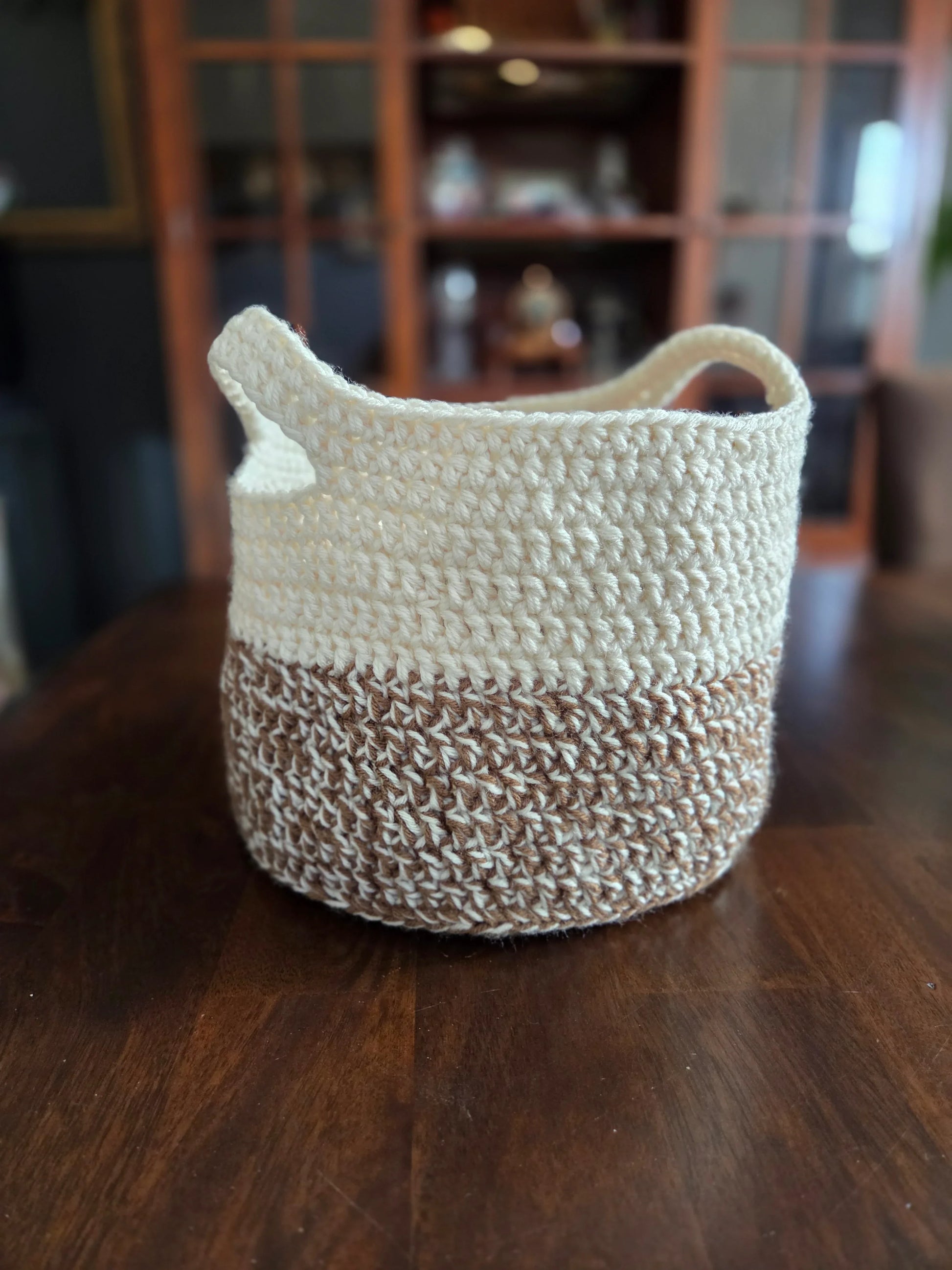 Handmade crochet storage basket in beige and brown on a wooden table
