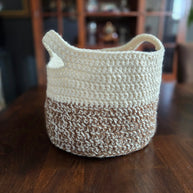 Handmade crochet storage basket in beige and brown on a wooden table