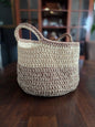 Handmade crochet storage basket with beige and brown yarn on a wooden table