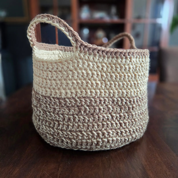 Handmade crochet storage basket with beige and brown yarn on a wooden table