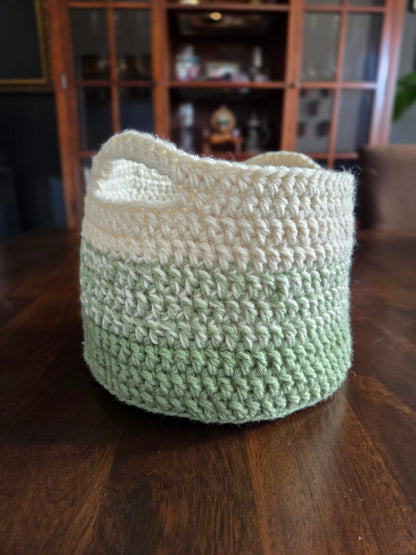 Handmade green and cream crochet basket on a wooden table, home decor storage.