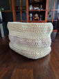 Handmade crochet basket with cream and pink yarn on wooden table