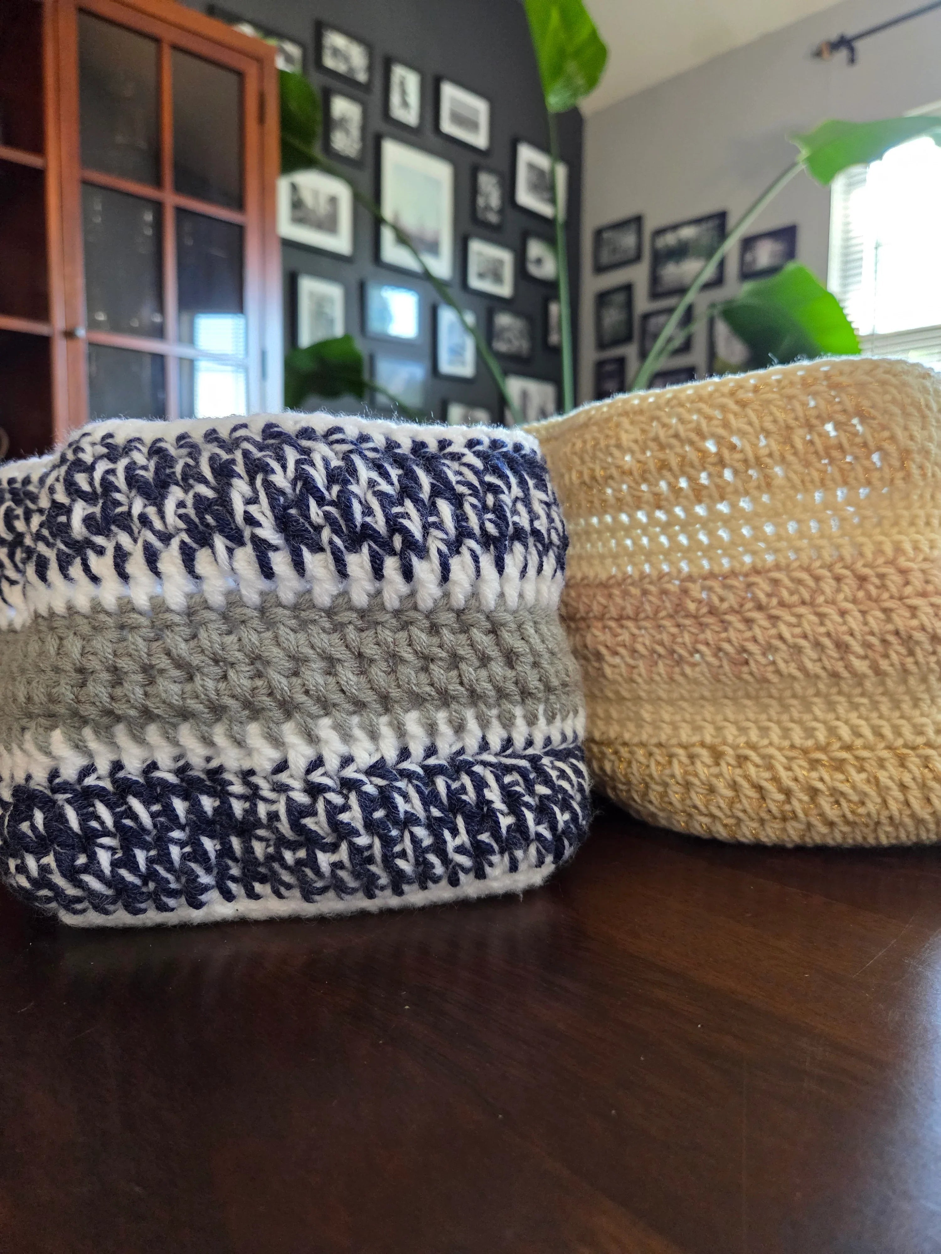 Handmade crochet baskets in blue, white, gray, and beige on a wooden table in a cozy room.