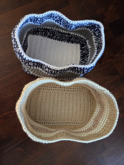 Two crochet storage baskets, one beige and one blue-white, on a dark wooden floor
