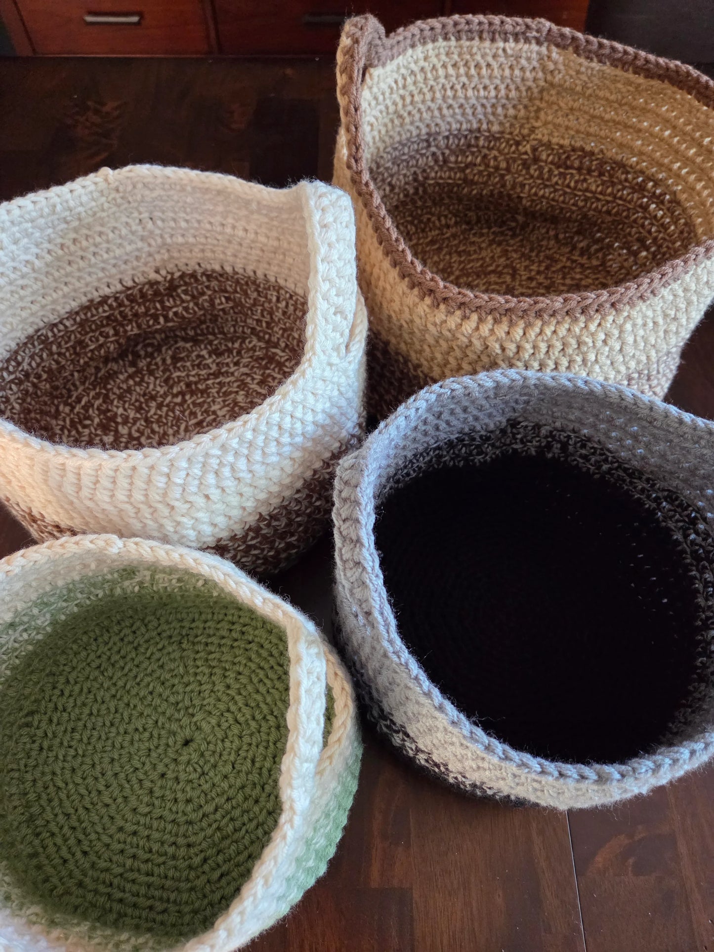 Set of four hand-crocheted storage baskets in natural colors on wooden surface