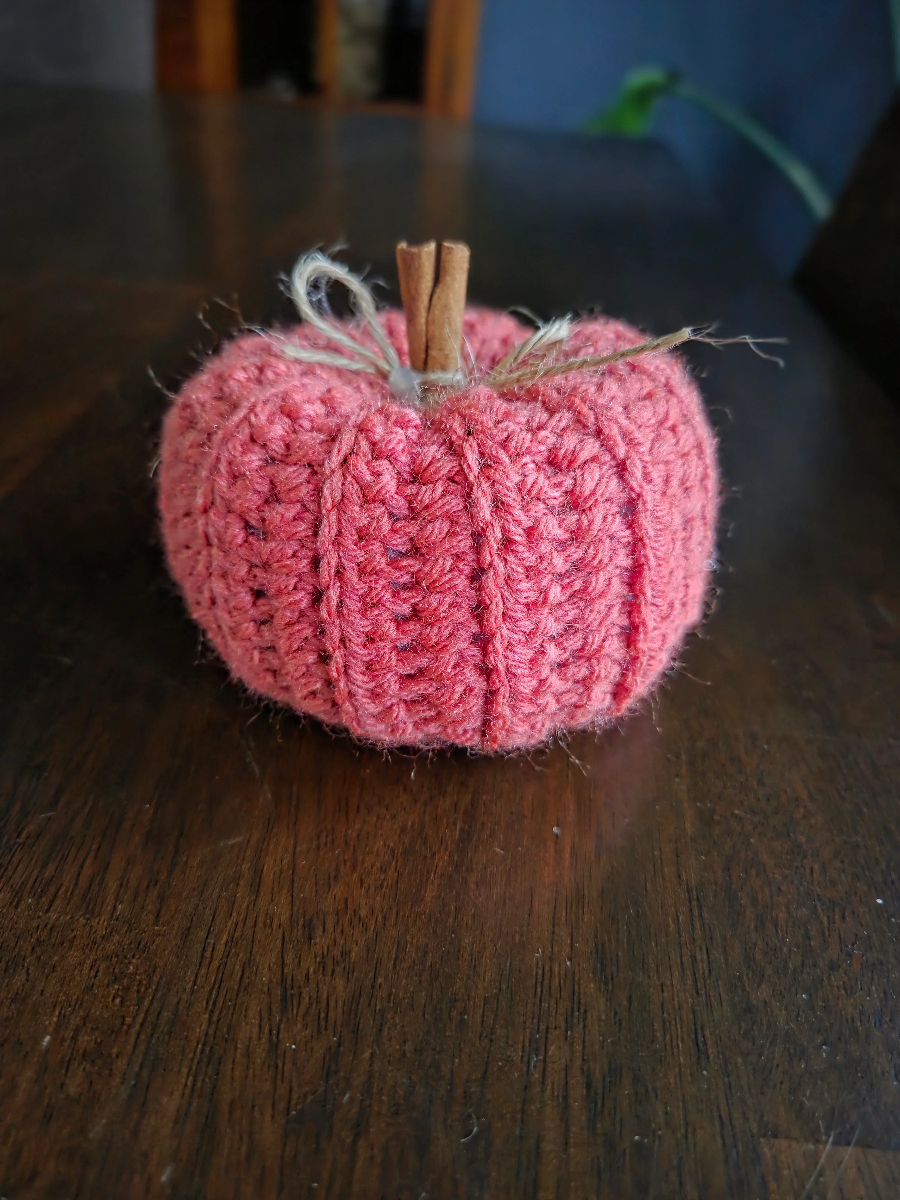 Handmade crochet pumpkin with cinnamon stick stem on a wooden table