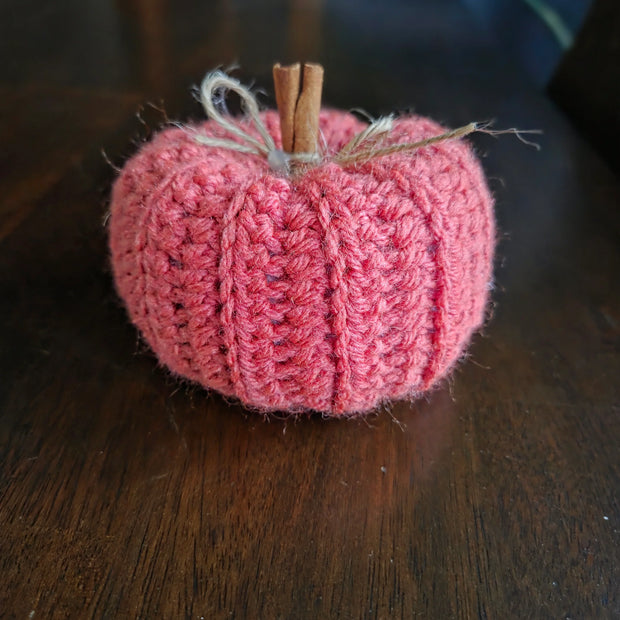 Handmade crochet pumpkin with cinnamon stick stem on a wooden table