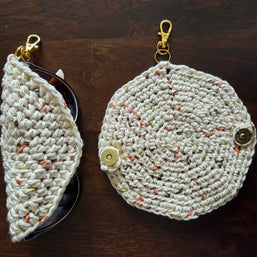 Handmade crochet eyeglass case with clasp, beige and speckled yarn, on wood surface