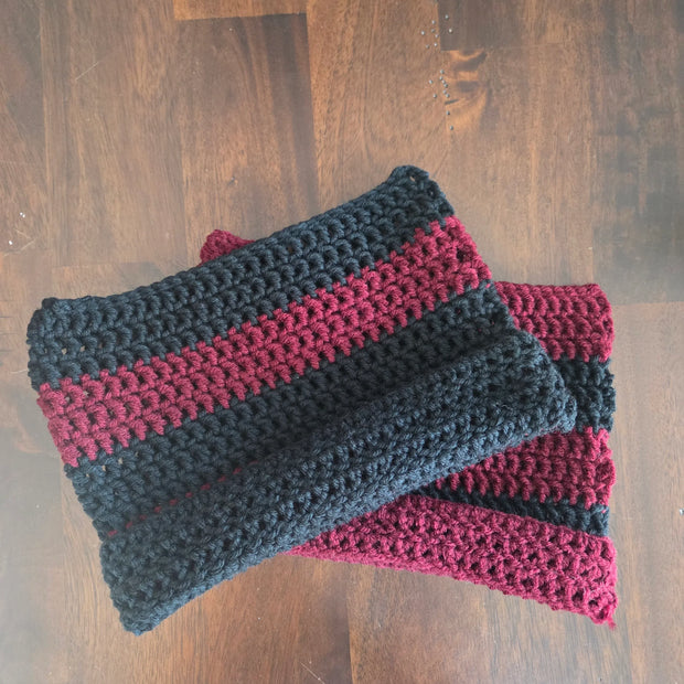 Handmade crochet scarf with black and burgundy stripes on a wooden table