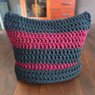 Handmade crochet cat ear hat with black and burgundy stripes on a wooden table