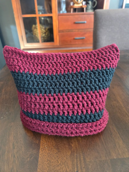 Handmade crochet basket with maroon and black stripes on a wooden table