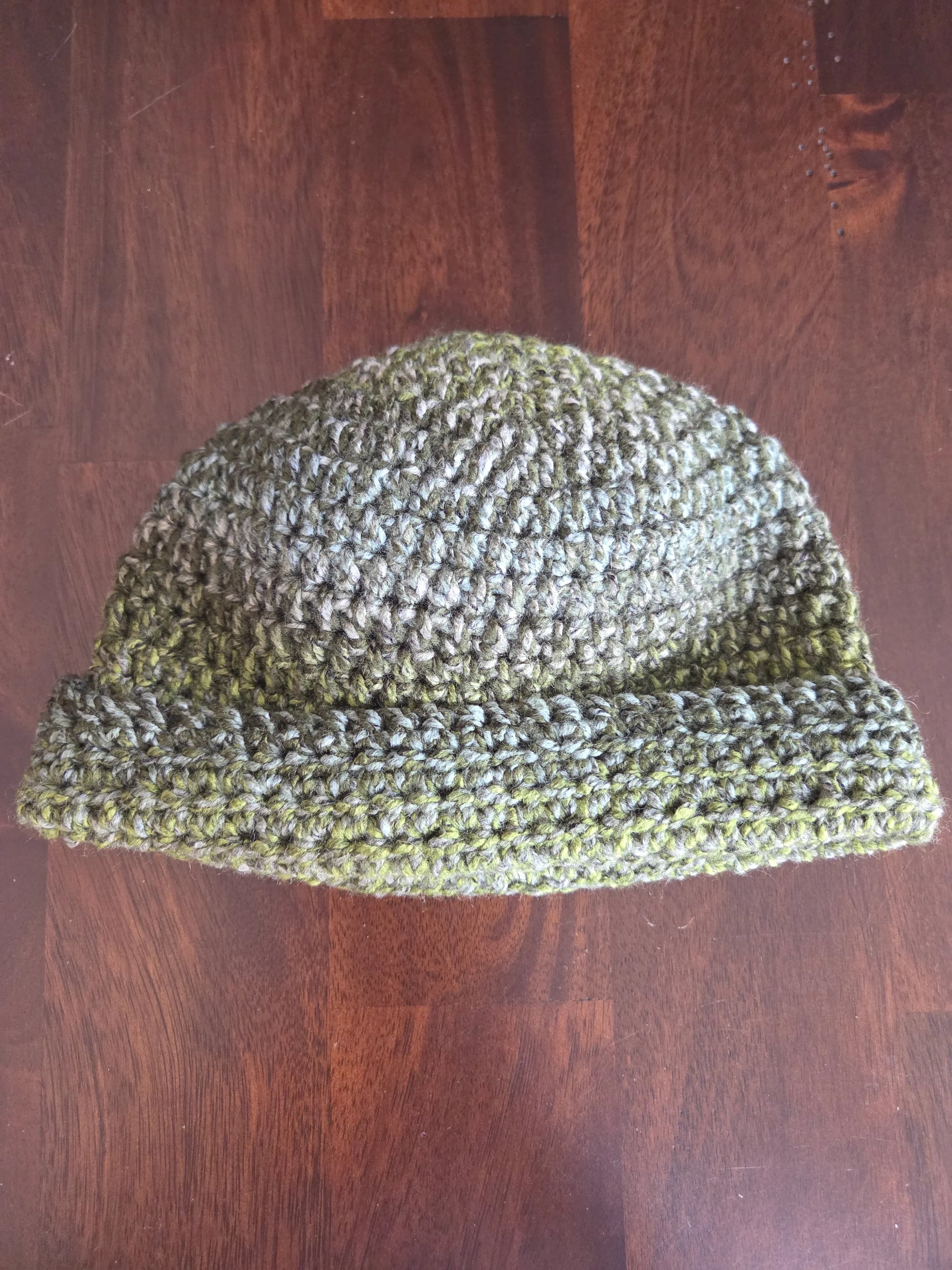 Handmade green crochet beanie hat on a wooden table