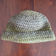 Handmade green crochet beanie hat on a wooden table