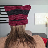 Woman wearing a handmade maroon and black crochet cat ear beanie indoors