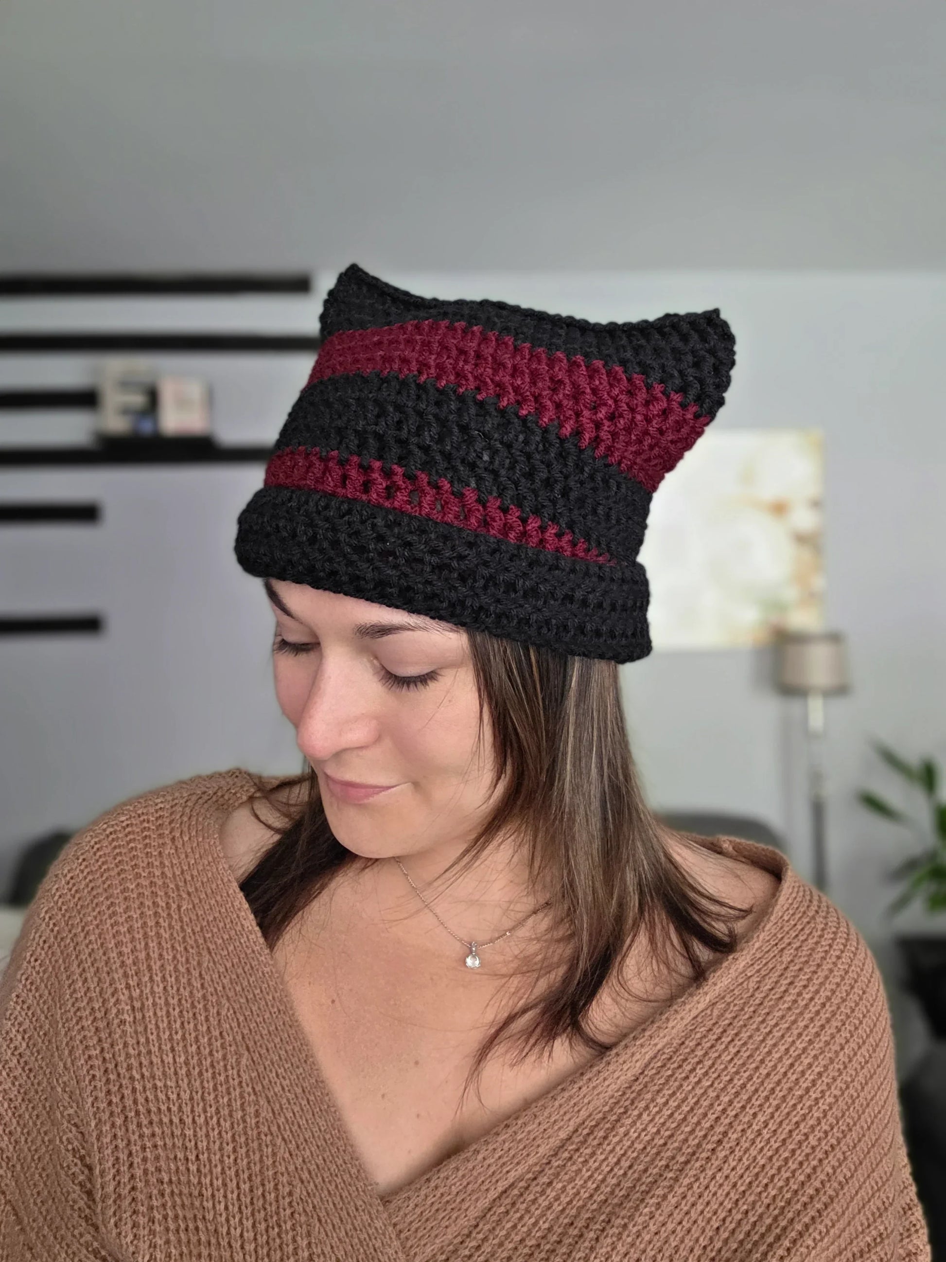 Woman wearing a handmade black and burgundy crochet cat ear beanie indoors