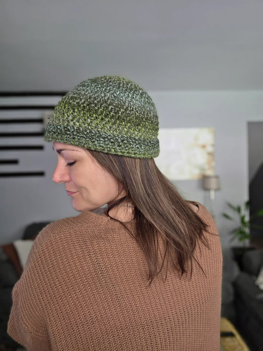 Woman wearing a green crochet beanie and brown knit sweater indoors