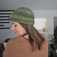 Woman wearing a green crochet beanie and brown knit sweater indoors