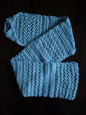 Light blue crocheted scarf with textured stitch pattern on dark background