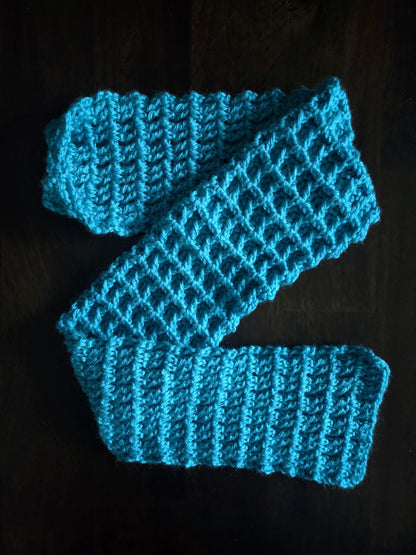Handmade bright blue crocheted scarf on a dark wooden surface