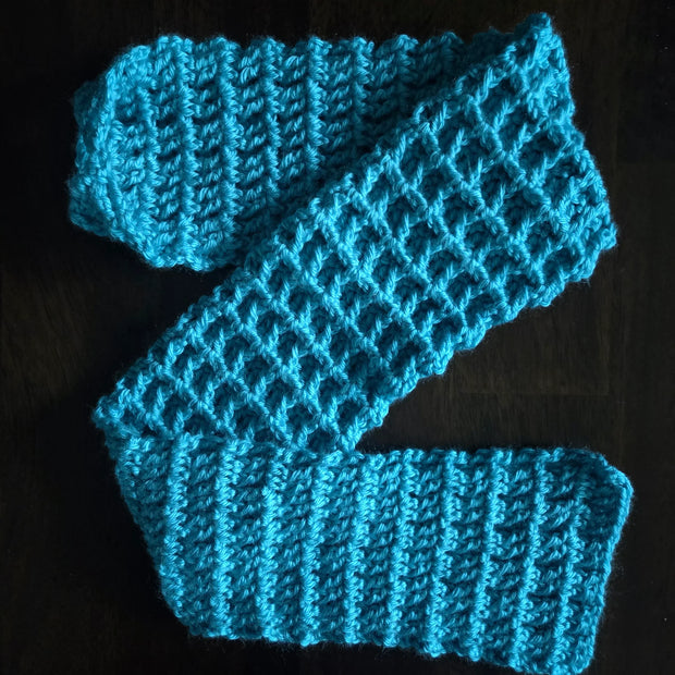 Handmade bright blue crocheted scarf on a dark wooden surface