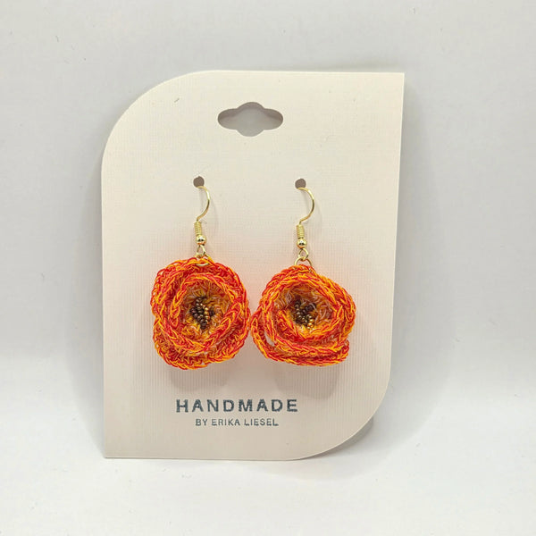 Handmade crochet flower earrings in vibrant orange and yellow, perfect for cozy, creative gifts.