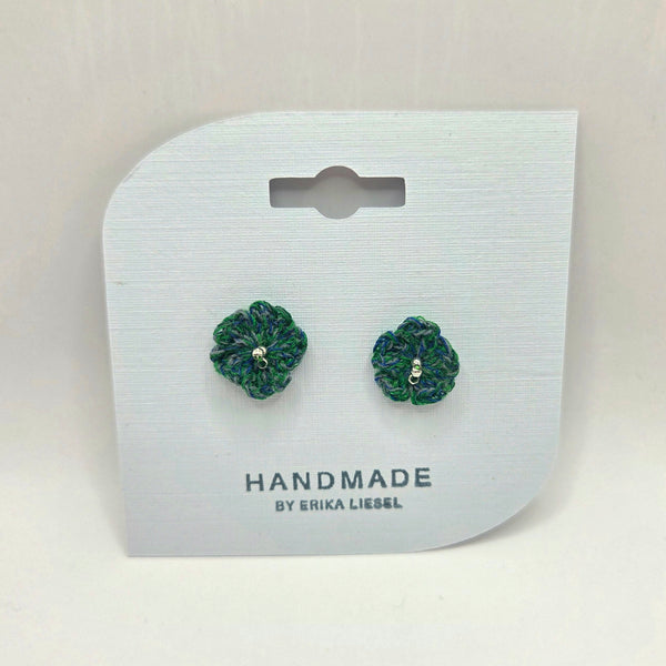 Handmade crochet flower earrings in green and blue, displayed on white card with 'Handmade by Erika Liesel' text.