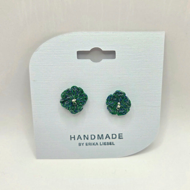 Handmade crochet flower earrings in green and blue, displayed on white card with 'Handmade by Erika Liesel' text.