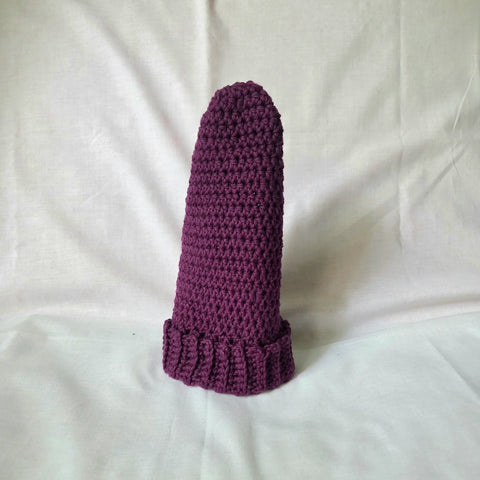 Handmade purple crochet sock with textured pattern and ribbed cuff on white fabric background