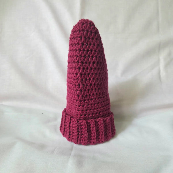 Handmade crochet gnome hat in deep pink, cozy textured knit with ribbed brim, perfect for whimsical decor or gifts