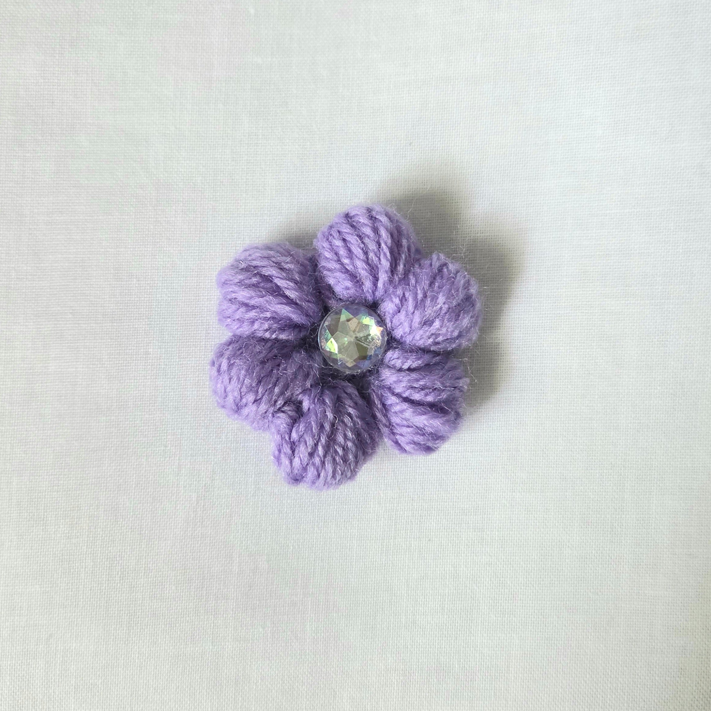Handmade lavender crochet flower pin with sparkling gem center, cozy craft gift