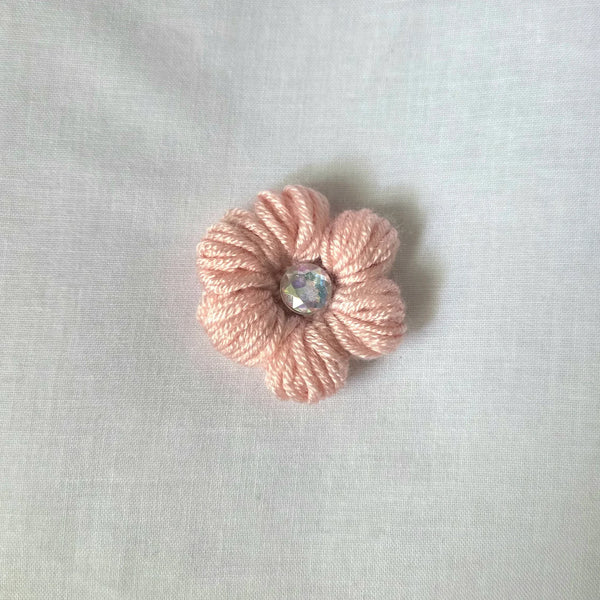 Handmade pink crochet flower pin with iridescent gem center, cozy craft gift
