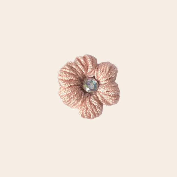 Handmade pink crochet flower pin with iridescent gem center, cozy craft gift