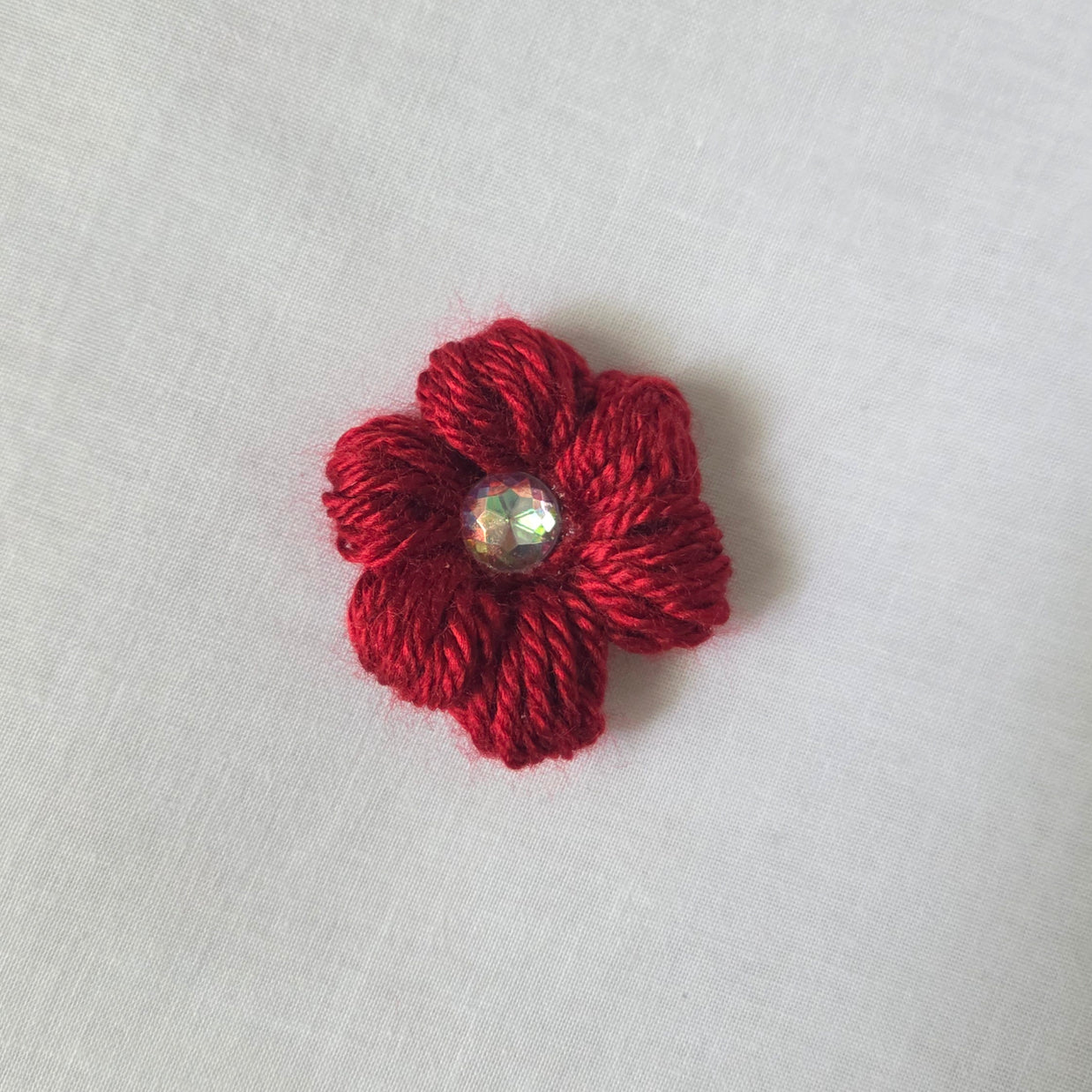 Red crochet flower brooch with sparkling gem center, handmade for cozy, creative gifts