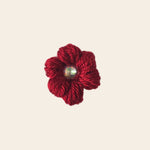 Handmade red crochet flower pin with sparkling gem center, cozy craft gift
