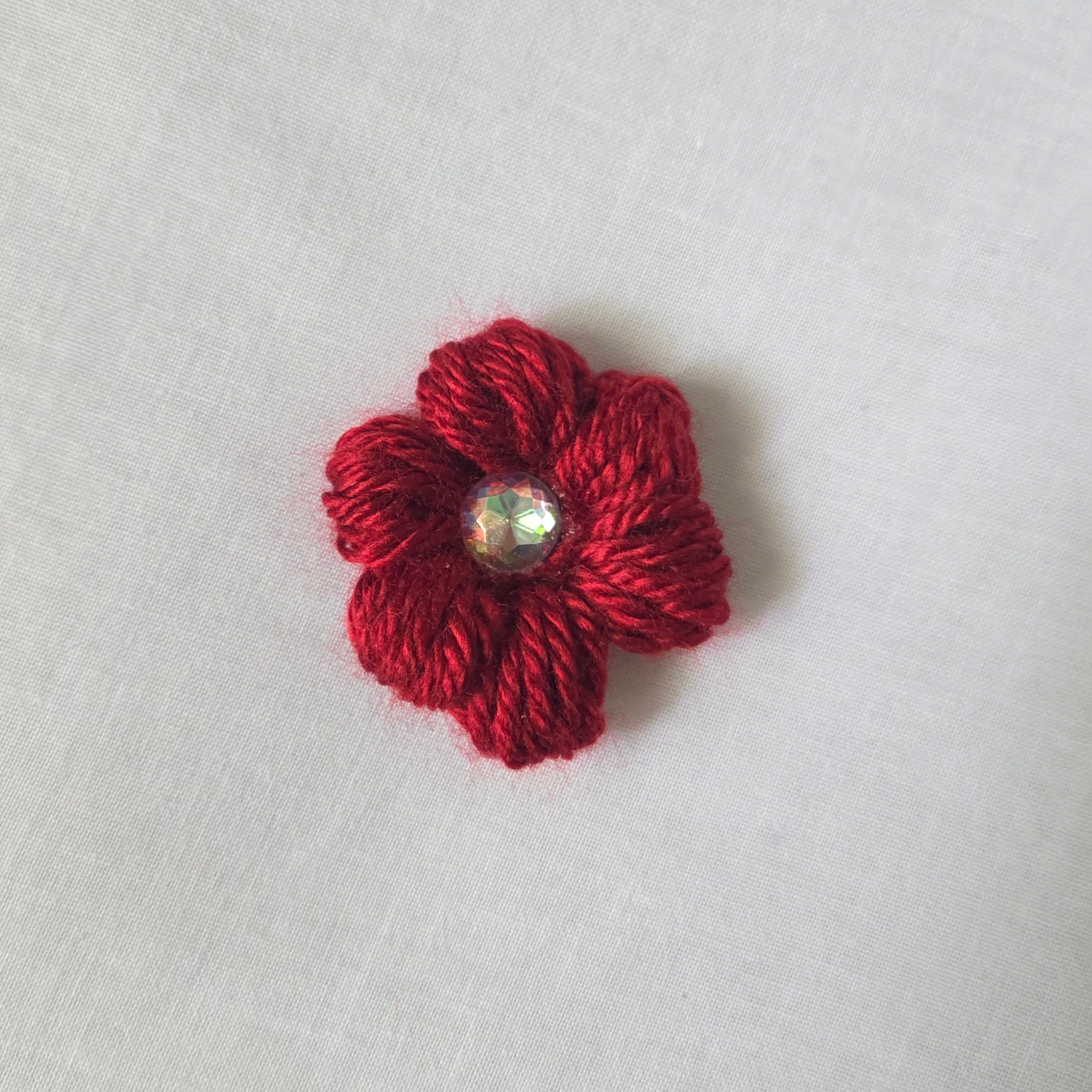 Red crochet flower brooch with sparkling gem center, handmade for cozy, creative gifts