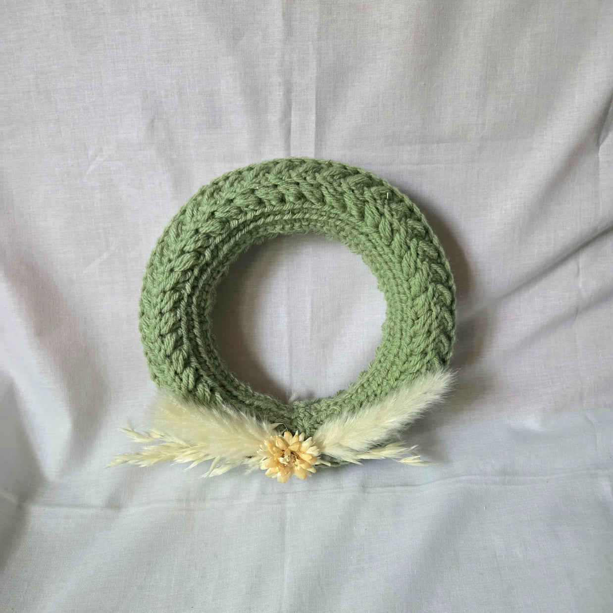 Handmade green crochet wreath with dried flowers and feathers, cozy home decor