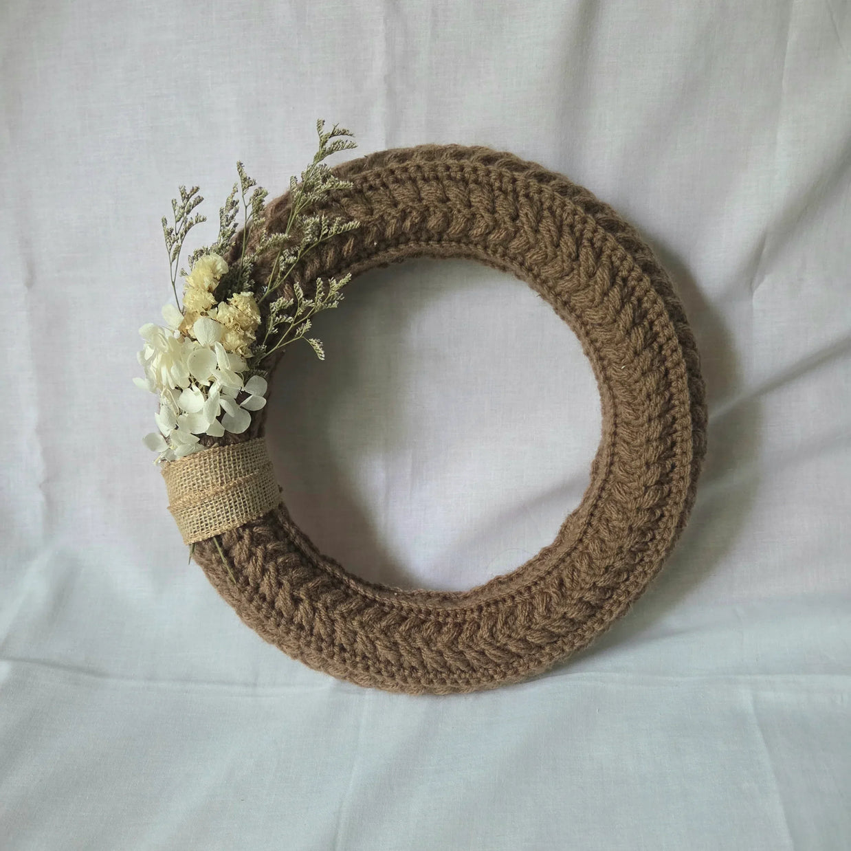 Handmade crochet wreath with dried flowers and burlap ribbon, cozy home decor