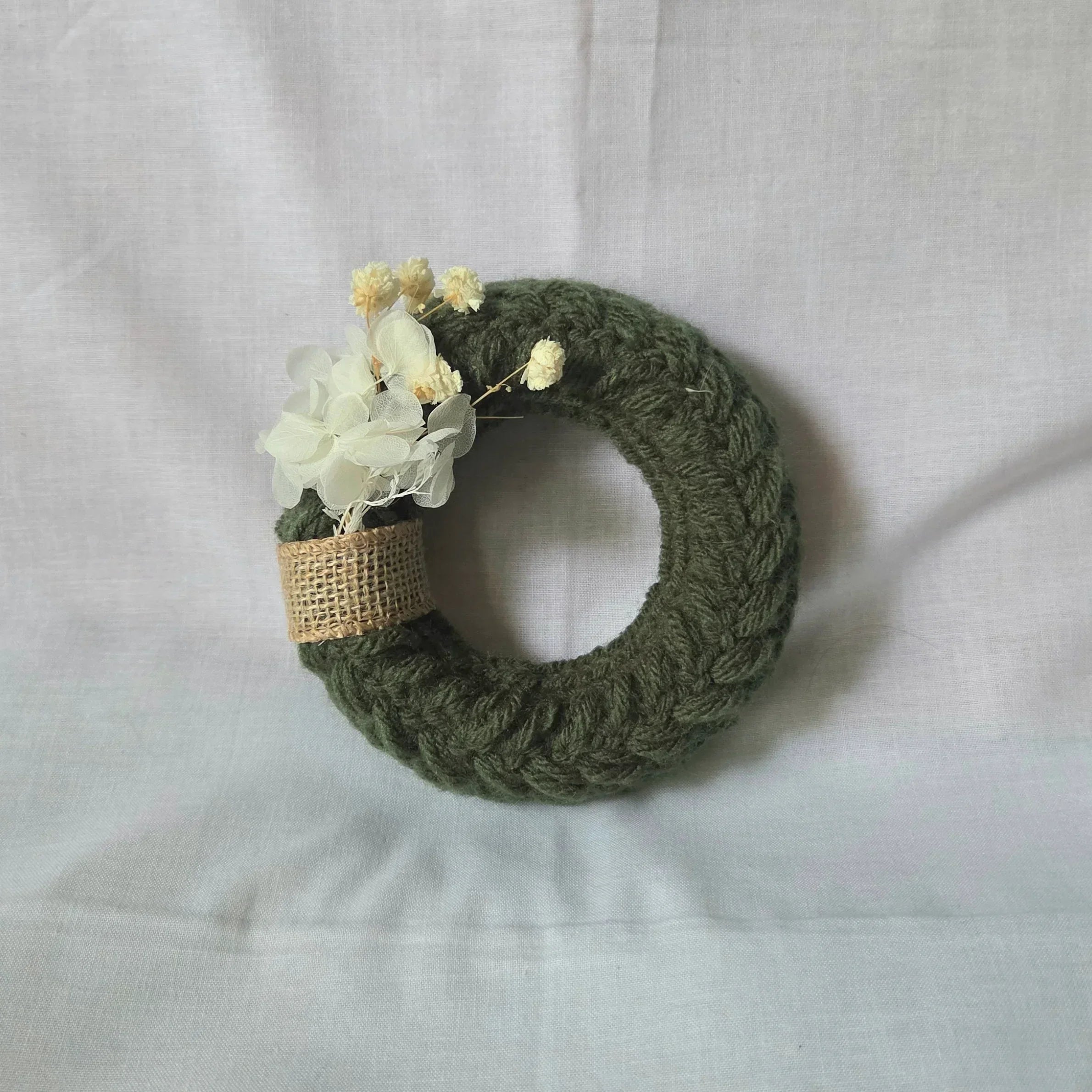 Handmade green crochet wreath with white flowers and burlap ribbon, cozy home decor
