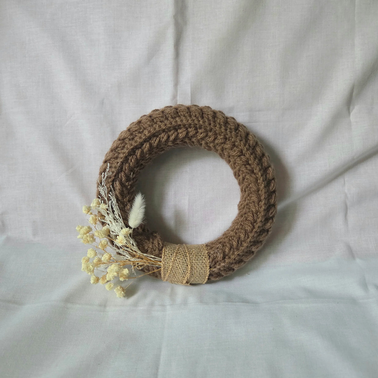 Handmade crochet wreath with dried flowers and burlap ribbon, cozy home decor
